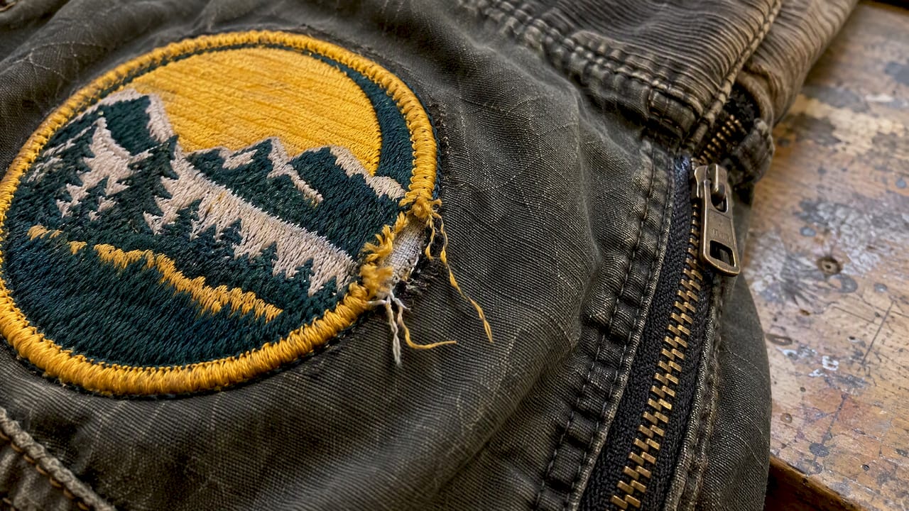 Frayed patch border beside a jacket zipper